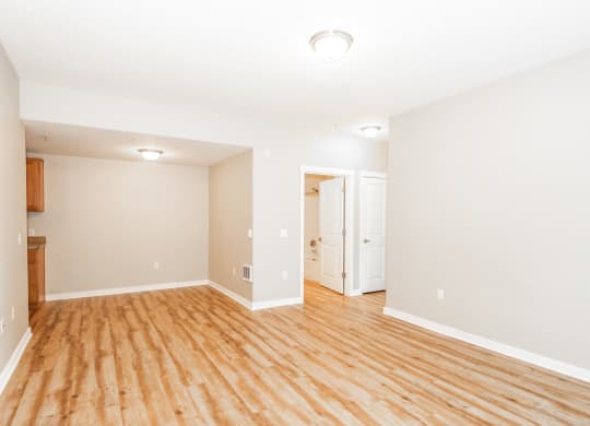 an empty living room with wood flooring and white walls