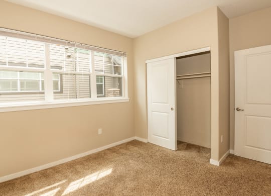 an empty bedroom with a window and a closet