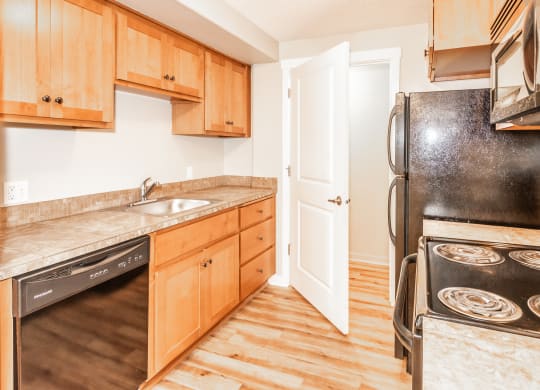 a kitchen with wooden cabinets and black appliances and a door to the refrigerator