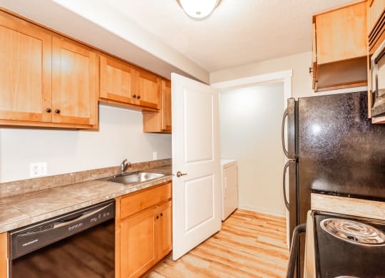 a kitchen with wooden cabinets and a black refrigerator and a sink