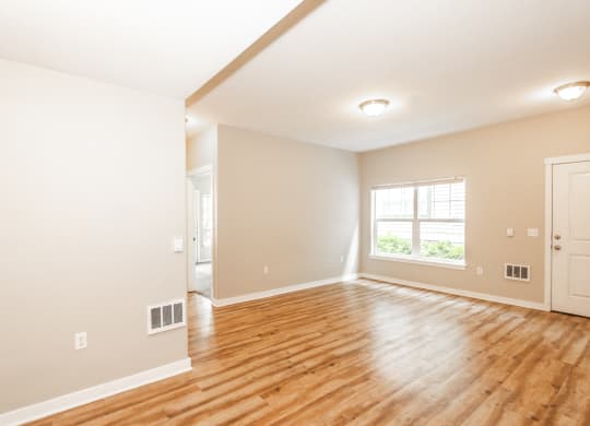 an empty living room with a hard wood floor and a window