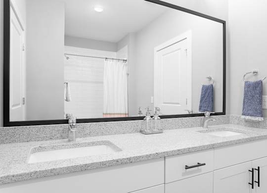A bathroom with a large mirror above a double sink vanity.