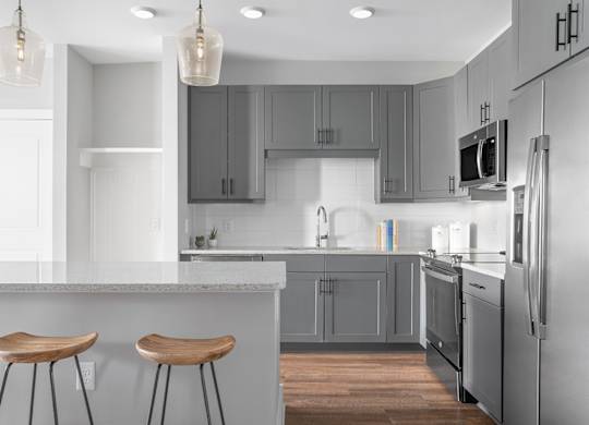 A modern kitchen with a white countertop and grey cabinets.