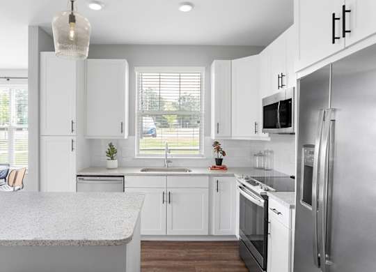 A modern kitchen with white cabinets and stainless steel appliances.