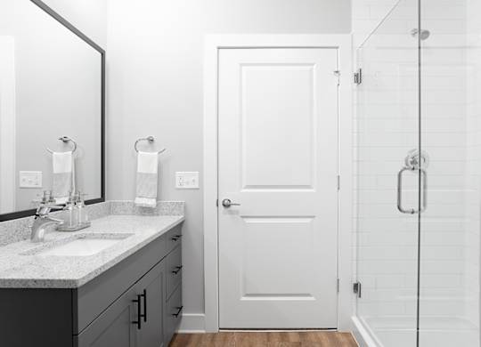 A white bathroom with a sink, mirror, and shower.