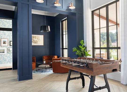 A foosball table sits in the middle of a room with blue walls and a large window.