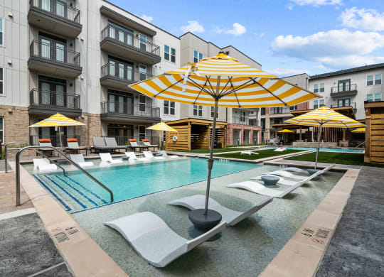 a swimming pool with yellow umbrellas and white lounge chairs