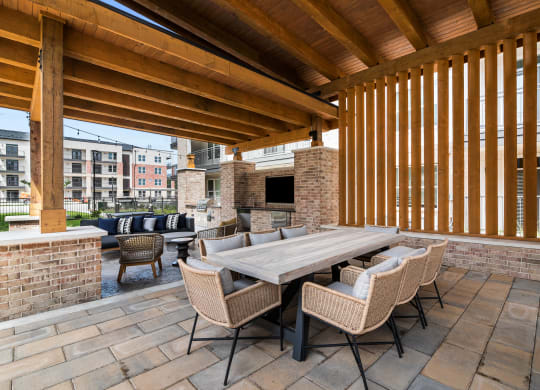 a covered patio with a large wooden table and chairs