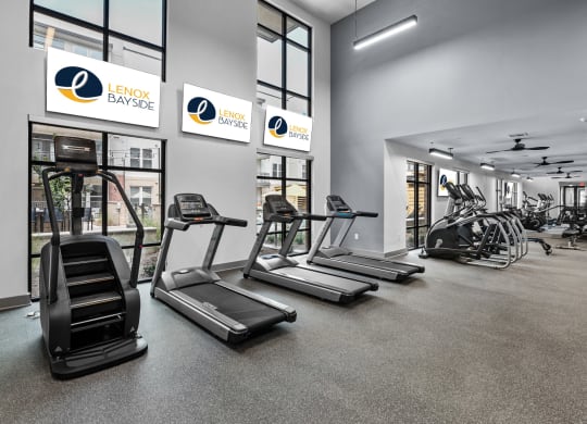 a gym with treadmills and other exercise equipment in a building with large windows