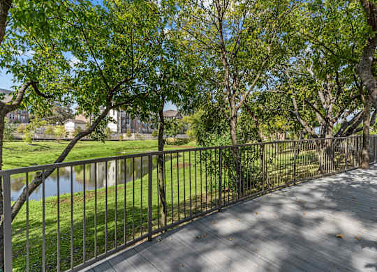 A wooden walkway with a metal railing runs through a grassy area.