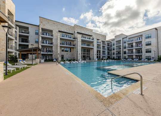 A large swimming pool is surrounded by apartment buildings.