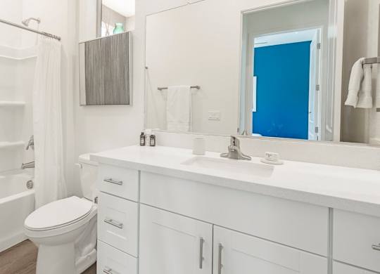 A white bathroom with a toilet, sink, and bathtub.