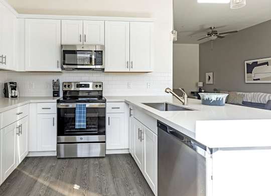 A modern kitchen with white cabinets and stainless steel appliances.