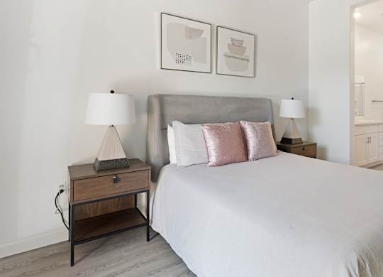 A bedroom with a large bed and two nightstands with lamps.