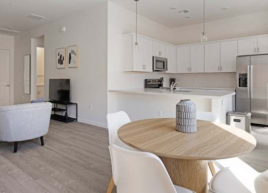 A modern kitchen and living room with white furniture and a grey sofa.