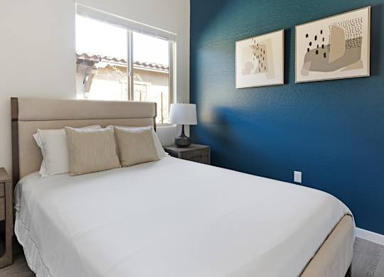 A bedroom with a large bed and two lamps.