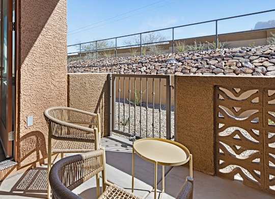 A patio with a table and chairs overlooking a rocky landscape.