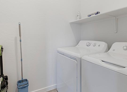 A white wall with a mop and a dustpan on it.