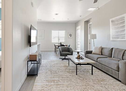 A living room with a grey couch and a white bed.