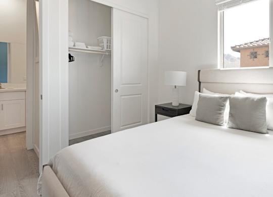 A white bed with a white headboard and two white pillows.