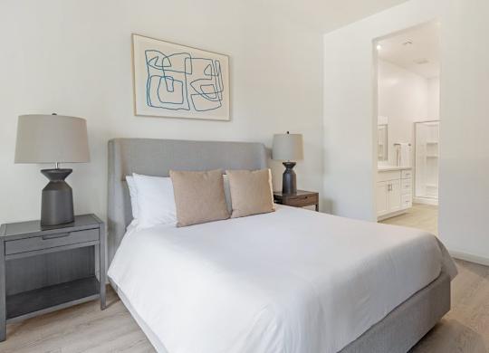 A bedroom with a bed, nightstand, and lamp.