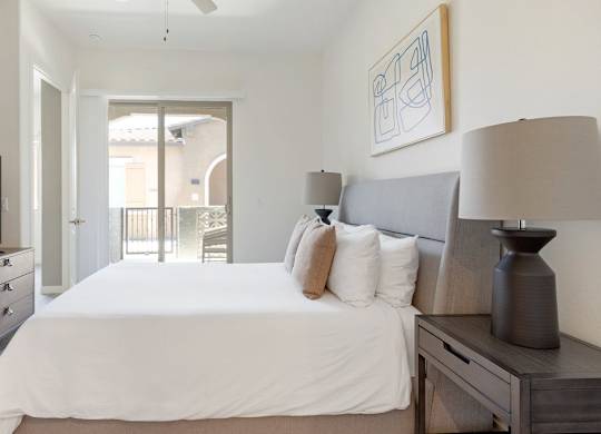 A bedroom with a large bed, a television, and a painting on the wall.