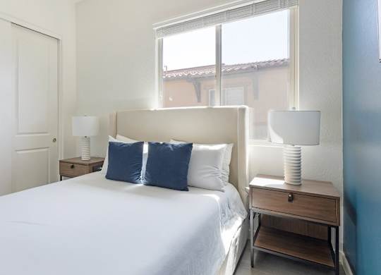 A bedroom with a large bed, two lamps, and a nightstand.