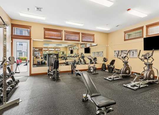 A gym with a variety of equipment including treadmills, weights, and exercise machines.