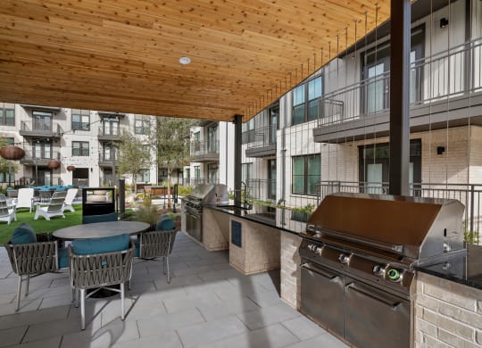a patio with a barbecue grill and a table with chairs