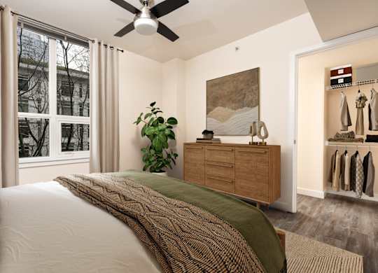 A bedroom with a bed, a ceiling fan, and a window with curtains.