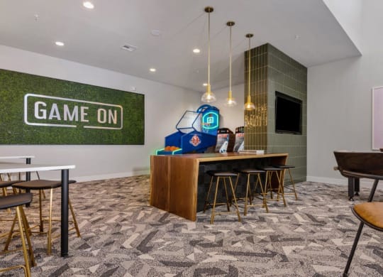 a game room with a bar and chairs and a game on screen