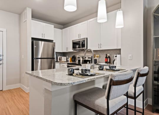 a kitchen with a marble counter top and a stainless steel refrigerator
