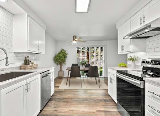 A modern kitchen with white cabinets and black appliances.