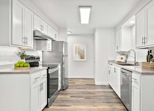 A modern kitchen with white cabinets and stainless steel appliances.