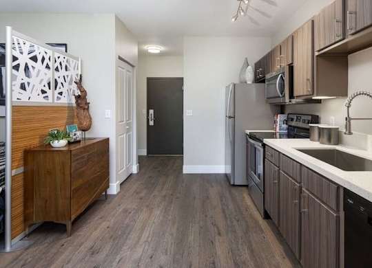 A kitchen with wooden floors and a black refrigerator.