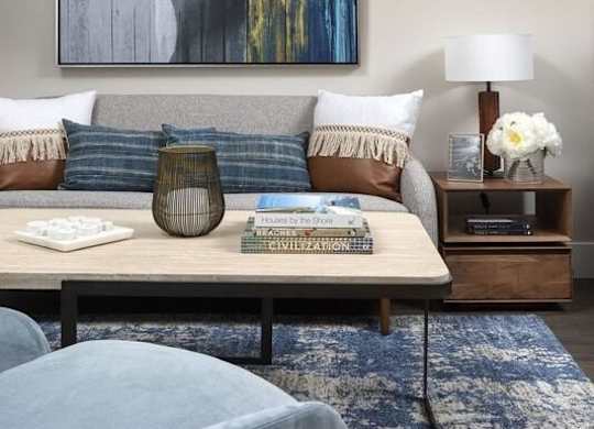 A living room with a blue rug and a grey armchair.