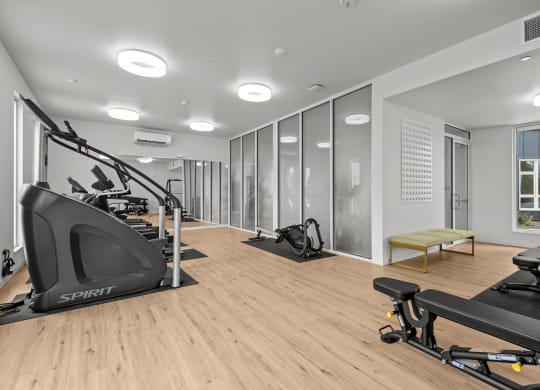 a gym with treadmills and other exercise equipment on a wood floor