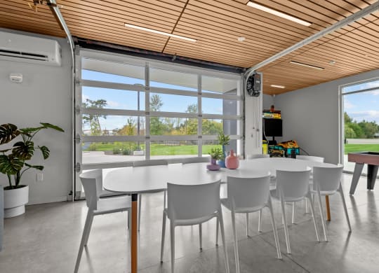 a dining room with white tables and chairs and large windows