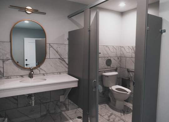 A bathroom with a marble wall and a round mirror above a sink.