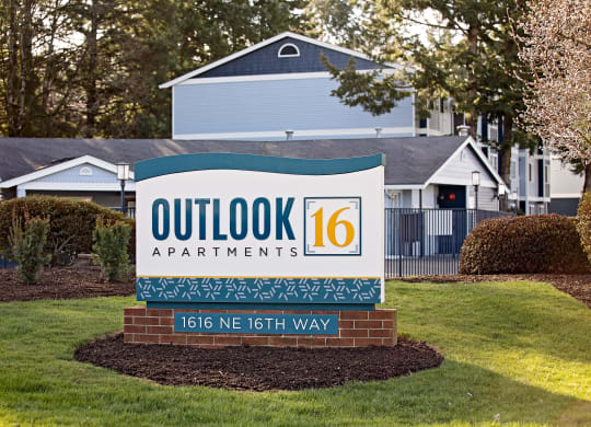 a sign that says outlook 16 apartments with a house in the background