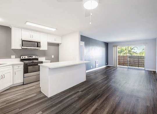 A kitchen with white cabinets and a wooden floor.