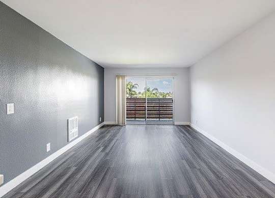 A room with grey walls and wooden flooring with a window and a door.