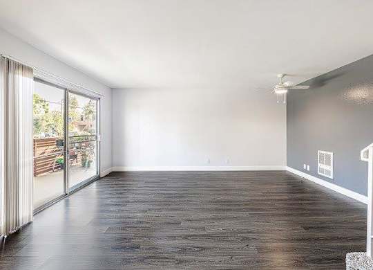 A spacious room with a sliding glass door leading to a balcony.