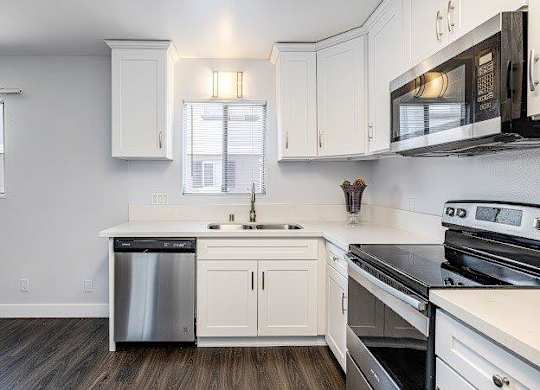 A kitchen with white cabinets and black appliances.
