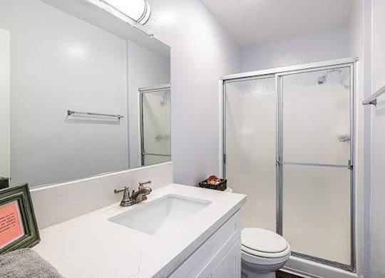 A white bathroom with a toilet, sink, and shower.