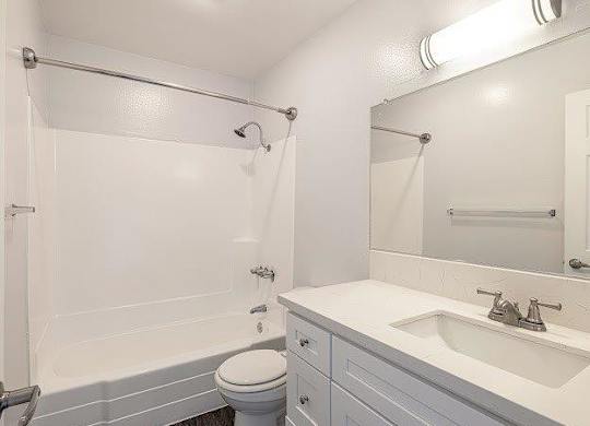 A white bathroom with a toilet, sink, and bathtub.