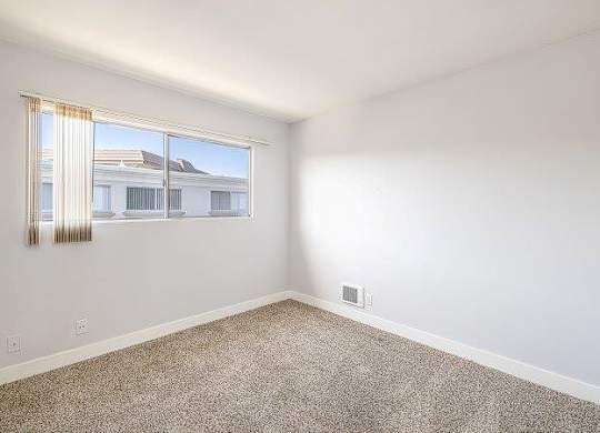 A room with a window and a carpeted floor.