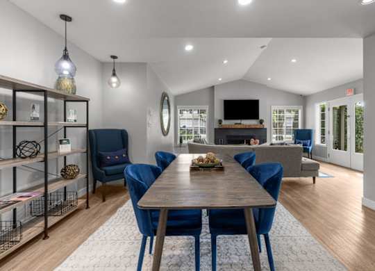 a living room with a wooden table and blue chairs