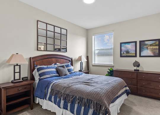 A bedroom with a bed, nightstand, and lamp.
