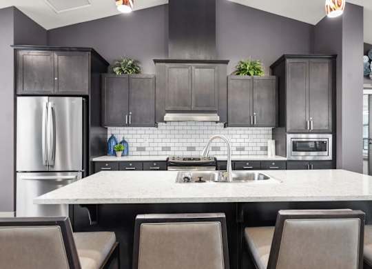 A modern kitchen with a large island and dark cabinets.